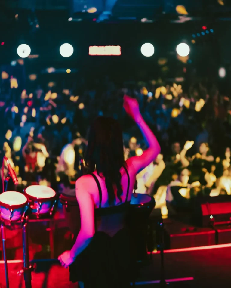 Kalabalık bir sahnede canlı darbuka şov, kırmızı sahne ışıkları