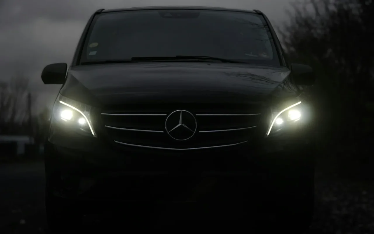 Farları yanan siyah Mercedes minivan